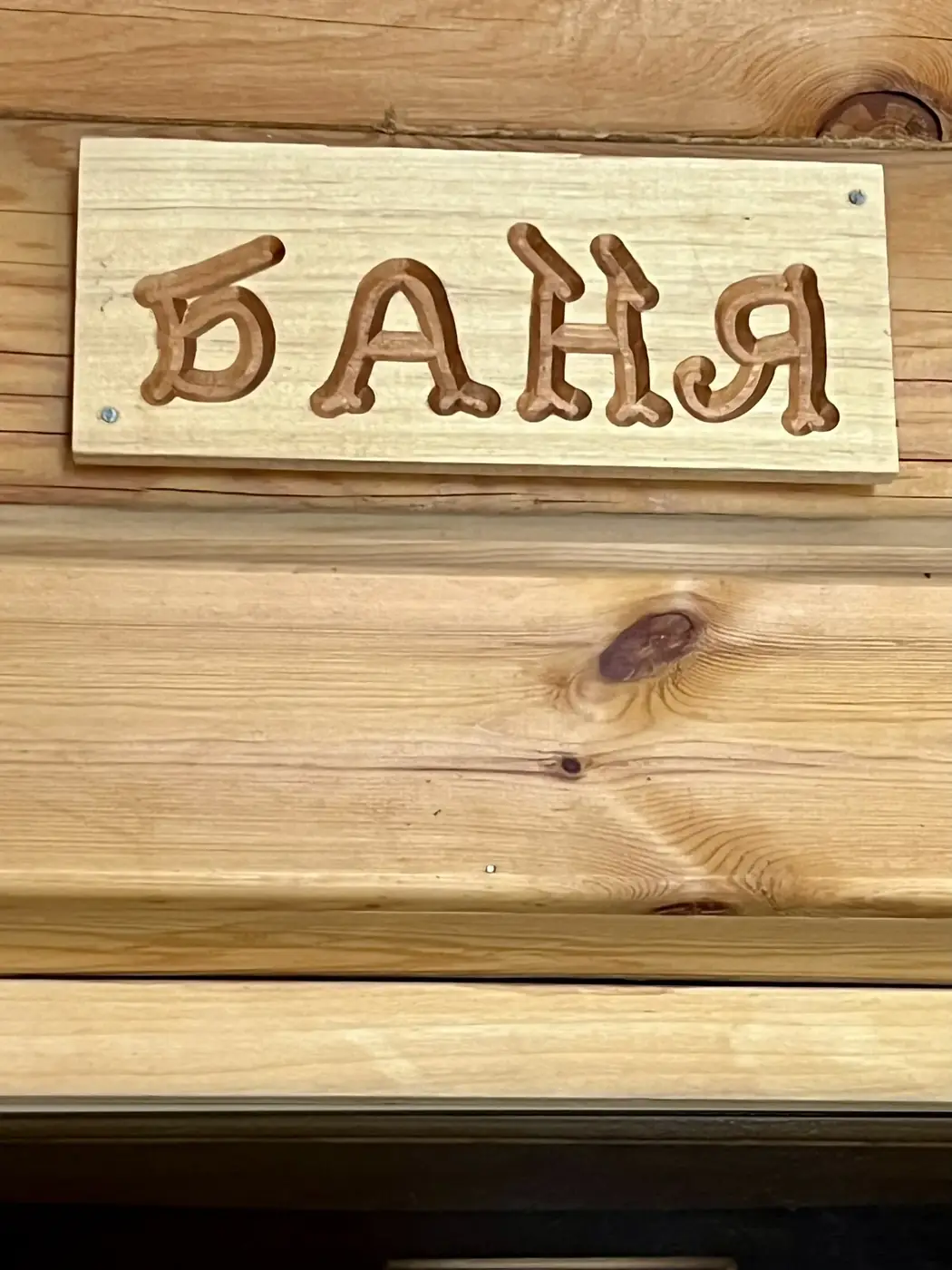 Табличка «Баня» на бревенчатой стене